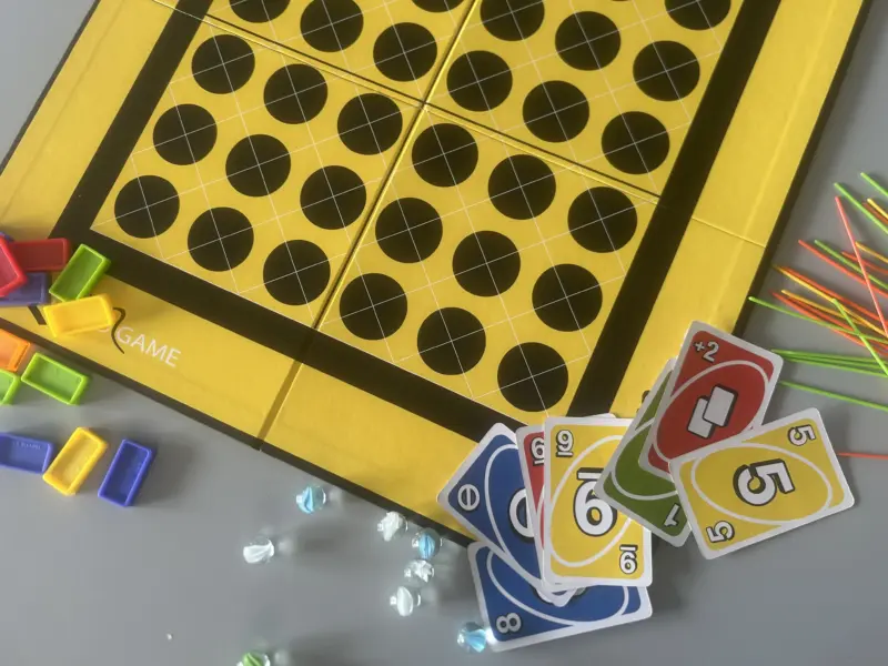 Board games, card games, marbles and pick up sticks laid out on a table