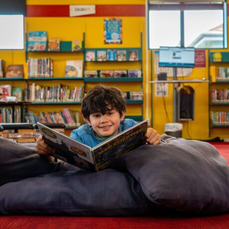 Boy reading a book while lying on beanbags at Roslyn Library