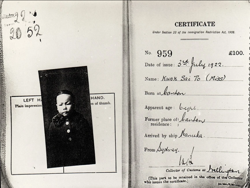 Two pages of a document. The left-hand page contains a passport-style photograph of a child wearing a winter coat. The facing page is headed "Certificate: Under section 33 of the Immigration Restriction Act, 1908" and includes information about the certificate-holder.