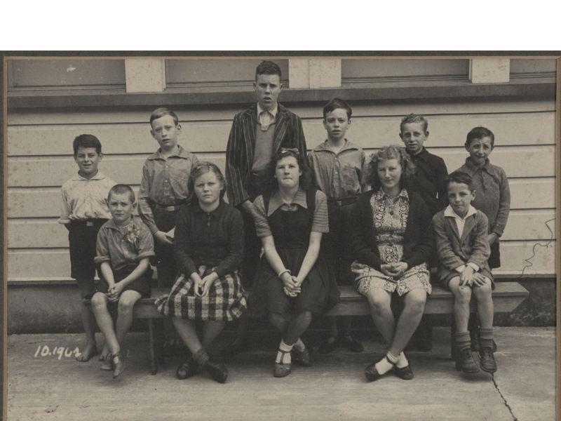 11 children in two rows, one row sitting in the front one row standing at the back.