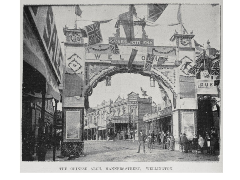 Black and white photo of an arch across a street that says Chinese Citizens Welcome with flags across the street.