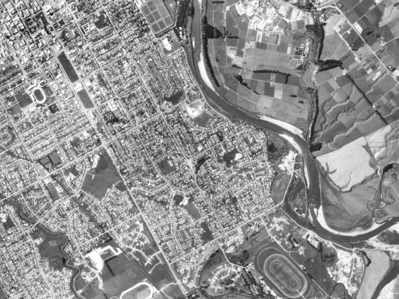 Black and white aerial photograph of Palmerston North, the Manawatū River is on the right-hand side, the Awapuni Racecourse is prominent on the bottom right and Te Marae o Hine -The Square is on the top left.