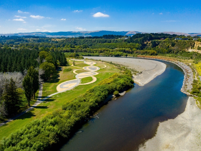 Aerial view of the Manawatū river with a bend to the left. Hills with windmills in the distance.