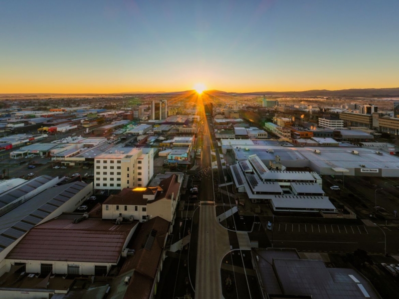 bird's eye view of a street bordered by buildings, with the setting sun aligned to the street.