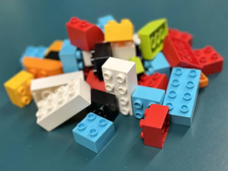 A small heap of multicoloured plastic blocks on a dark blue surface